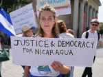 Mielenosoittaja ja Justice & Democracy for Nicaragua -kyltti