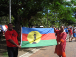 Kaksi miestä kantaa saarivaltion alkuperäiskansa kanakkien lippua vaalitilaisuudessa. 